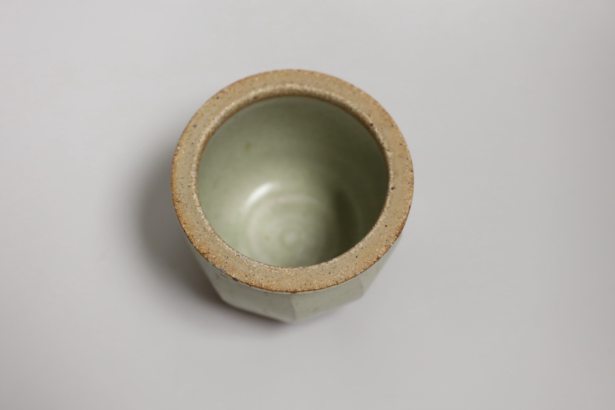 Richard Batterham (1936 – 2021), a cut sided stoneware jar and pointed cover with sage coloured glaze. 10.5cm high